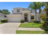 Charming two-story home features a well-manicured lawn, two-car garage and mature palm tree at 10216 Summer Azure Dr, Riverview, FL 33578