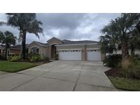 Charming home featuring a spacious three-car garage, lush landscaping, and a well-maintained lawn at 11341 Durham St, Parrish, FL 34219