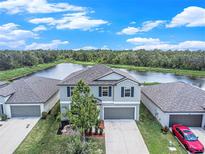 Two-story home boasts a lake view, large driveway, and attached two-car garage at 1655 Blue Rose Dr, Ruskin, FL 33570