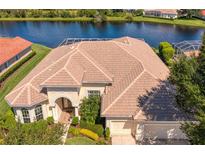 Aerial view of home with tile roof, lush landscaping, and a serene lake view at 17921 Arbor Haven Dr, Tampa, FL 33647