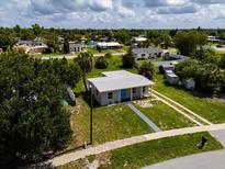 Inviting home featuring a gray exterior, a blue front door, and a spacious lawn at 21536 Holdern Ave, Port Charlotte, FL 33952