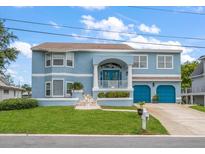 Charming two-story blue home with a well-manicured lawn, blue garage doors, and a welcoming front porch at 316 Hillpoint Dr, Palm Harbor, FL 34683