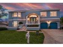 Charming blue two-story home featuring a manicured lawn and two-car garage, perfect for Gathering living at 316 Hillpoint Dr, Palm Harbor, FL 34683