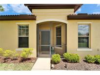 Charming home featuring a screened entrance, manicured landscaping, and neutral exterior paint at 5422 Sunset Falls Dr, Apollo Beach, FL 33572