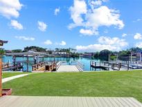 Picturesque backyard features a lush lawn, waterside dock, and beautiful water views on a sunny day at 599 Westwinds Dr # 9, Palm Harbor, FL 34683