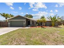 Charming single-story home featuring a well-maintained lawn, mature tropical landscaping, and a two-car garage at 6921 8Th Street E Ct, Sarasota, FL 34243