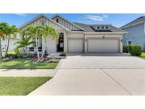 Charming home with a two-car garage, manicured lawn, palm trees, and beautiful landscaping at 7420 Paradiso Dr, Apollo Beach, FL 33572