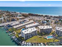 Breathtaking aerial view of waterfront condos, marina, and sandy beach with turquoise ocean waters at 9755 Harrell Ave # 101, Treasure Island, FL 33706