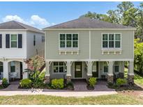 Charming exterior of a two-story home featuring a cozy front porch with green doors and neatly landscaped surroundings at 106 Cutlass Way, Oldsmar, FL 34677