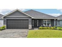 Charming one-story home with a paved driveway, manicured lawn, and a two-car garage in a modern color scheme at 12937 Ogden Glade Rd, Dade City, FL 33525
