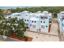 Stunning exterior view of townhomes with white roofs, light blue facades and charming blue awnings at 1413 Bayshore Blvd # 11, Dunedin, FL 34698