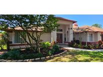 Inviting single-story home with mature landscaping and a charming red door at 16502 Windsor Park Dr, Lutz, FL 33549