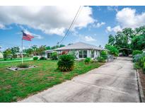 Charming single-story home featuring a metal roof, lush lawn, and an American flag waving proudly at 2060 Saffold Park Dr, Ruskin, FL 33570