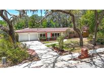 Charming single-story home featuring a red brick facade, white exterior, and manicured landscaping at 327 Sunnyside Rd, Temple Terrace, FL 33617
