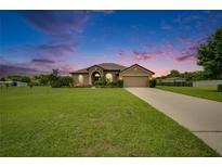 Charming home with a well-manicured lawn, fountain and a two-car garage at sunset at 3411 Knoxville Pl, Plant City, FL 33566