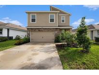 Two-story home with a tan exterior, stone accents, a two-car garage and landscaped front yard at 3528 Maple Grove Way, Plant City, FL 33565