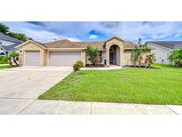 Charming single-story home featuring a manicured lawn, a two-car garage, and beautiful brickwork at 4211 Elba Pl, Valrico, FL 33596