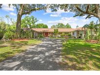 Spacious home with mature trees, charming front entrance, and long driveway leading to the home at 10193 Wallien Dr, Brooksville, FL 34601