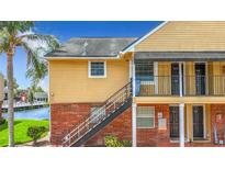 Exterior shot of a yellow condo building with brick foundation and stairs leading to the second floor entrances at 200 Country Club Dr # 202, Largo, FL 33771