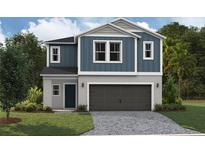 Two-story home with blue and gray siding, a two-car garage, and a well-manicured lawn at 37106 Sagemoor Dr, Zephyrhills, FL 33541