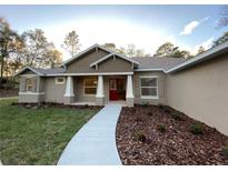 Inviting single-story home with a red front door, manicured landscaping, and a welcoming walkway at 6153 La Pine Rd, Brooksville, FL 34602