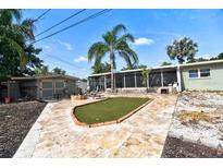 A delightful backyard features a decorative grass pad and a spacious screened-in porch with elegant tile flooring at 6912 14Th N St # 6912, St Petersburg, FL 33702