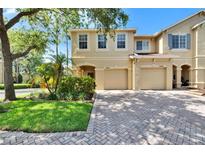 Charming two-story home featuring a two-car garage, landscaped yard, and brick-paved driveway at 10606 Shady Falls Ct, Riverview, FL 33578