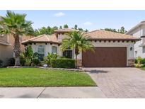 Charming single-story home featuring a tile roof, brick driveway, and lush tropical landscaping at 10880 Cory Lake Dr, Tampa, FL 33647