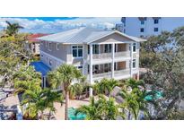Beautiful three-story home featuring balconies, a pool, and lush palm trees surrounding the property at 1204 Derby Ln, Sarasota, FL 34242