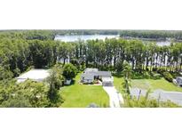 An aerial view of a home with a lush lawn surrounded by trees and views of the adjacent lake at 19209 Crooked Ln, Lutz, FL 33548