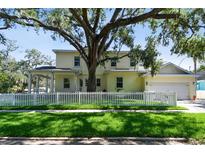Charming two-story home featuring a white picket fence, lush lawn, and mature tree providing ample shade at 238 7Th S Ave, Safety Harbor, FL 34695