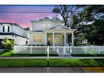 Inviting two-story home featuring a covered front porch, a white picket fence, and a beautifully landscaped front yard at 238 7Th S Ave, Safety Harbor, FL 34695