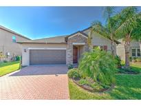 Charming single-Gathering home featuring a brick driveway and a manicured front yard at 25200 Lambrusco Loop, Lutz, FL 33559