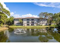 Condo building overlooking a serene pond with a fountain in a lush, landscaped community at 2650 Countryside Blvd # C204, Clearwater, FL 33761