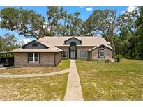 Charming brick home featuring a manicured lawn and an inviting walkway to the front entrance at 31949 Amberlea Rd, Dade City, FL 33523