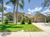Charming home featuring a two-car garage, mature landscaping, and manicured lawn at 4335 Clairidge Way, Palm Harbor, FL 34685
