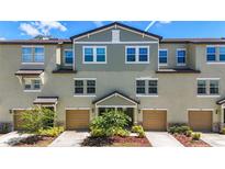 Exterior shot of multiple townhomes with tan garages and landscaping, featuring an appealing facade at 4567 Tuscan Loon Dr, Tampa, FL 33619