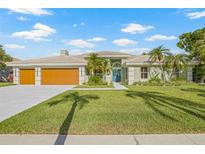 Beautiful one-story home with a large two car garage, a light green exterior, and tropical landscaping at 5002 E Longboat Blvd, Tampa, FL 33615