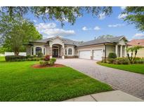 Stunning home showcasing lush landscaping, a paver driveway, and a three-car garage at 505 Vintage Way, Brandon, FL 33511