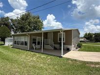 Charming mobile home with a covered porch, well-maintained lawn, and a sunny sky at 5105 Wood St, Zephyrhills, FL 33542