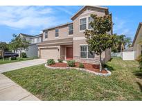 Two-story home featuring manicured lawn, landscape, and a neutral-colored stucco exterior at 7641 Armonk Ln, Wesley Chapel, FL 33545