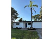 Single-story home with white exterior, black trim, landscaping and brick walkway, set against a blue sky at 7703 Glenview Ln, Tampa, FL 33615