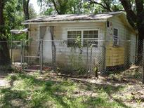 Exterior view of a small, weathered home with a chain-link fence at 8617 Broad St, New Port Richey, FL 34654