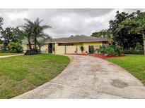Charming one-story home with a well-manicured lawn, a beautiful curved driveway, and mature palm trees at 1117 S Florida Ave, Tarpon Springs, FL 34689