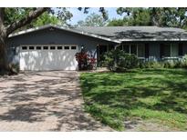 Charming single-story home with a brick driveway, manicured lawn, and attached two-car garage at 12794 Palm Dr, Largo, FL 33774