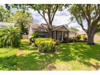 Charming single-story home featuring mature trees, lush landscaping, and a well-manicured lawn at 15028 Redcliff Dr, Tampa, FL 33625