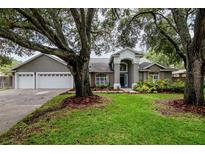 Charming home with a well-manicured lawn, lush landscaping, and mature trees providing shade and curb appeal at 18004 Clear Lake Dr, Lutz, FL 33548