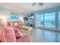 Bright living room with plush coral sofas and a sliding glass door to the ocean view balcony at 18610 Gulf Blvd # 607, Indian Shores, FL 33785