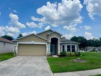 Charming single-Gathering home featuring a manicured lawn, two-car garage and arched entryway, perfect for suburban living at 25327 Seven Rivers Cir, Land O Lakes, FL 34639