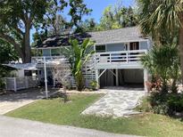 Charming light blue two-story home with a white deck, open garage and tropical landscaping at 401 Pennsylvania Ave, Crystal Beach, FL 34681